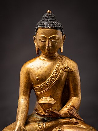 Close-up of the Nepali bronze Buddha statue showing the face, chest and robe border