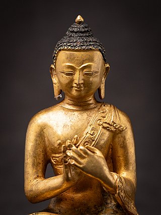 Nahaufnahme des Gesichts der nepalesischen Bronze-Buddha-Statue mit Lockenhaar und Ohrläppchen