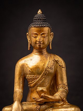 Portrait view of the Nepali bronze Buddha, showing elongated earlobes and the bowl