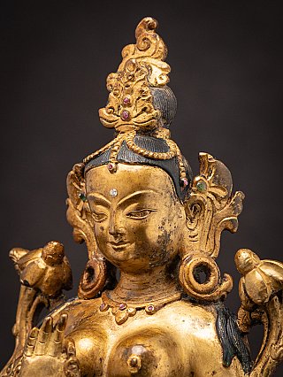 Three-quarter face detail of the Green Tara bronze statue with crown and ear ornament