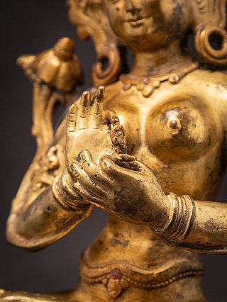 Hands close-up of the Green Tara bronze statue showing dharmachakra mudra near the chest