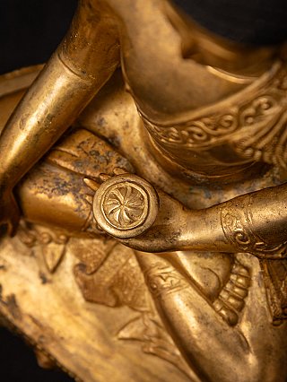 Schuin detail van de schoot met kom in de hand en gegraveerde patronen op het brons