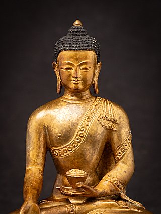 Nepali gilded bronze Buddha statue face detail, frontal view with curled hair