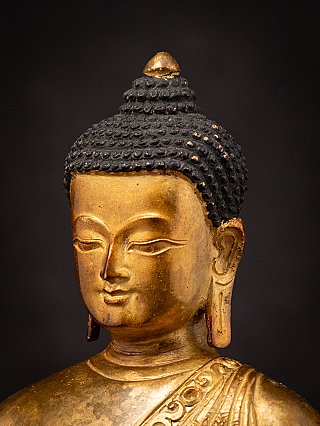 Nepali gilded bronze Buddha statue face detail, three-quarter right view with topknot