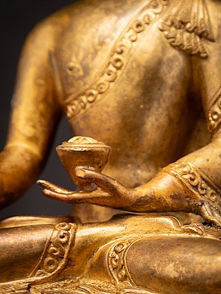 Bowl and hand detail with robe strap across the chest, gilded bronze Nepali Buddha