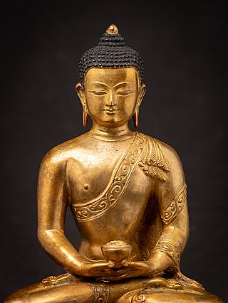 Chest and head detail of the Nepali bronze Buddha statue with robe band and downcast eyes