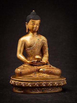Seated Nepali bronze Buddha statue with bowl and inlaid robe, angled front view