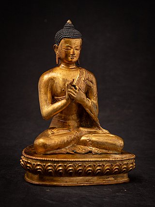 Nepali bronze Buddha statue seated with Dharmachakra mudra, angled front view on lotus base