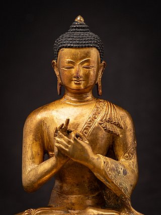 Upper body detail of a Nepali bronze Buddha statue with Dharmachakra mudra and robe border