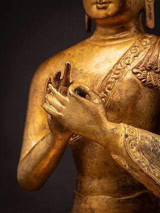 Close-up of a Nepali bronze Buddha statue hands in Dharmachakra mudra with robe border