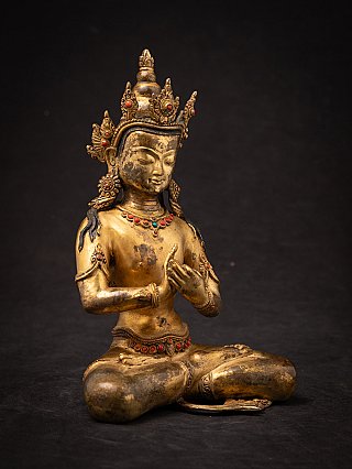 Nepali bronze Buddha statue with crown in three-quarter right view, showing face and mudra