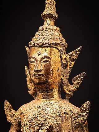 Close-up face detail of a Thai bronze Buddha statue with crown band and ear ornament