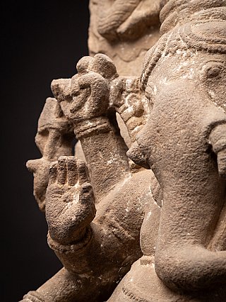 Detail of Ganesha’s raised hand and arm on the sandstone relief, with carved background