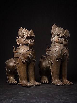 Pair of Burmese bronze temple lion statues, three-quarter right view with head and chest details