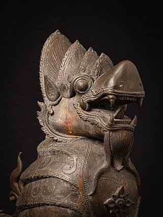 Head detail of a Burmese bronze temple lion with open mouth, fangs and engraved crest