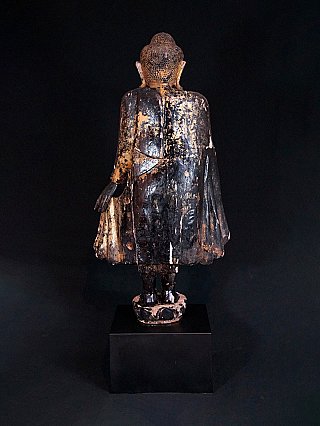 Standing Burmese Buddha statue in wood, rear view showing worn surface and robe