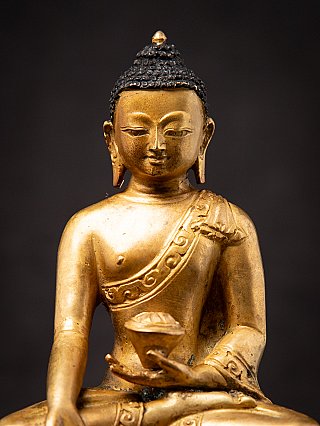 Front face close-up of the Nepali bronze Buddha statue with elongated ears