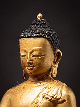 Three-quarter portrait detail of the Nepali bronze Buddha statue, showing earlobe and hairline