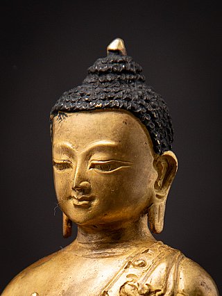 Three-quarter face detail of the Nepali bronze Buddha with ushnisha