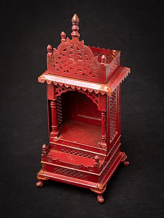 Nepali wooden shrine seen from above at an angle, with open niche and pierced crest
