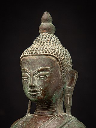 Three-quarter close-up of the bronze Buddha head showing facial modelling and patina