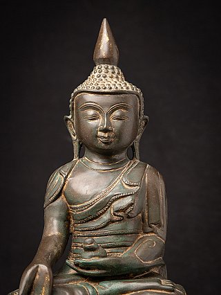 Face detail of Burmese bronze Buddha showing ushnisha and incised robe edge