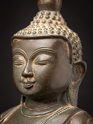 Close-up of Burmese bronze Buddha face with light wear around nose and lips