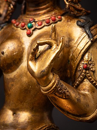 Detail of the Green Tara bronze raised hand with bracelet and visible patina on the arm