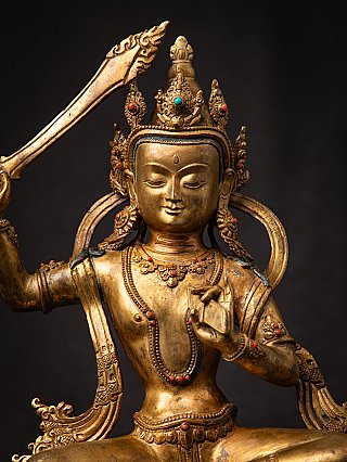 Upper-body view of a Nepali bronze Manjushri statue with crown and sword blade visible