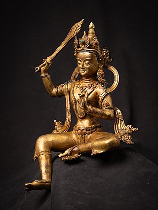 Bronze Manjushri statue from Nepal with sword raised above the head, three-quarter view