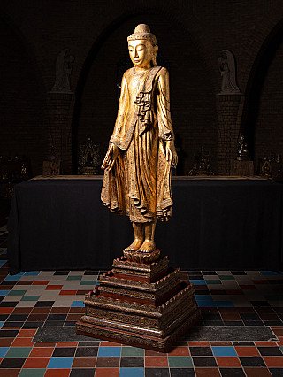 Stehende Buddha-Statue aus Holz aus Myanmar in Dreiviertelansicht mit schräg sichtbarem Sockel