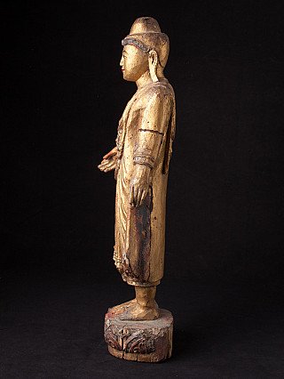 Standing Buddha statue in wood, side profile view with robe and arm
