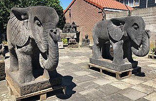 Paar Indonesische lavastenen olifantenbeelden op sokkel, in de buitenlucht schuin van voren