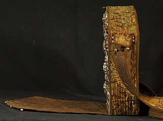 Seitenansicht des nepalesischen Gao mit Brokatbezug, Trageriemen und Metallkante