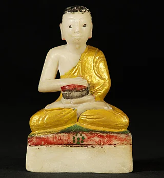 Burmese monk statue in marble, seated holding an alms bowl, full front view