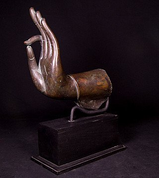 Thai bronze Buddha hand, angled view on a black display base in vitarka mudra