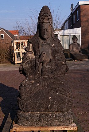 Große Lavastein-Guan-Yin aus Indonesien, sitzend auf Sockel, Frontalansicht im Freien