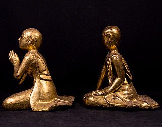 Burmese wooden monk statues, side view; left with folded hands, right with lowered arm