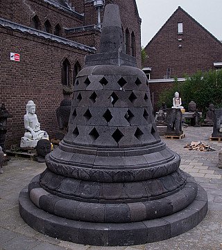Indonesische lavastenen stupa in driekwartaanzicht, met diamantvormige openingen in de koepel