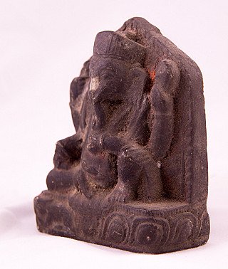 Houten Ganesha uit Nepal in driekwartaanzicht, met dikke blokachtergrond en slurf naar voren