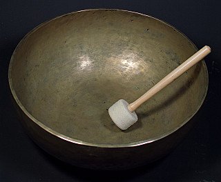 Große nepalesische Klangschale aus Bronze mit Holzklöppel, schräg von oben gesehen