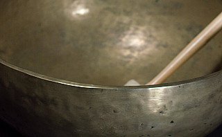 Detail des Randes der nepalesischen Klangschale aus Bronze, mit Klöppel im Hintergrund