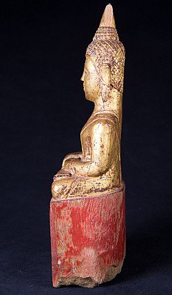 Antique Thai wooden Buddha statue seated, left side profile with pointed topknot and red base
