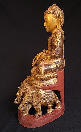 Wooden Buddha statue on elephant throne, left side profile with carved elephants