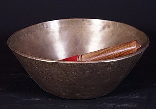 Nepali bronze singing bowl, angled view with wooden striker resting inside