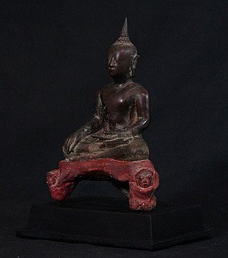 Thai bronze Buddha statue seated on red base, three-quarter left view