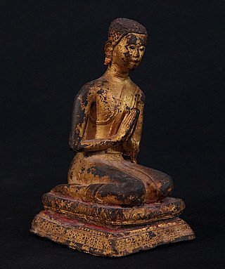Antique Thai bronze monk statue seated with hands in namaskara, three-quarter left view