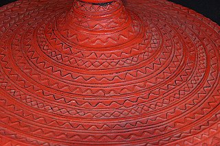 Close-up of incised zigzag and band patterns on the red lacquered lid