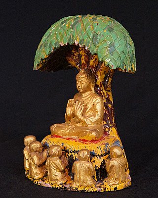 Sitzende Buddha-Statue unter dem Bodhi-Baum aus Holz, Dreiviertelansicht links mit kleinen Figuren am Sockel
